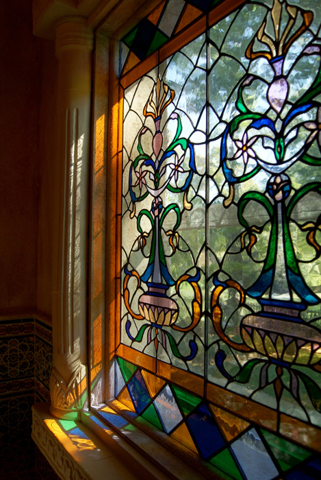 Detail of a stained glass window with Art Nouveau floral pattern in blue, green, orange, yellow, and white leaded glass