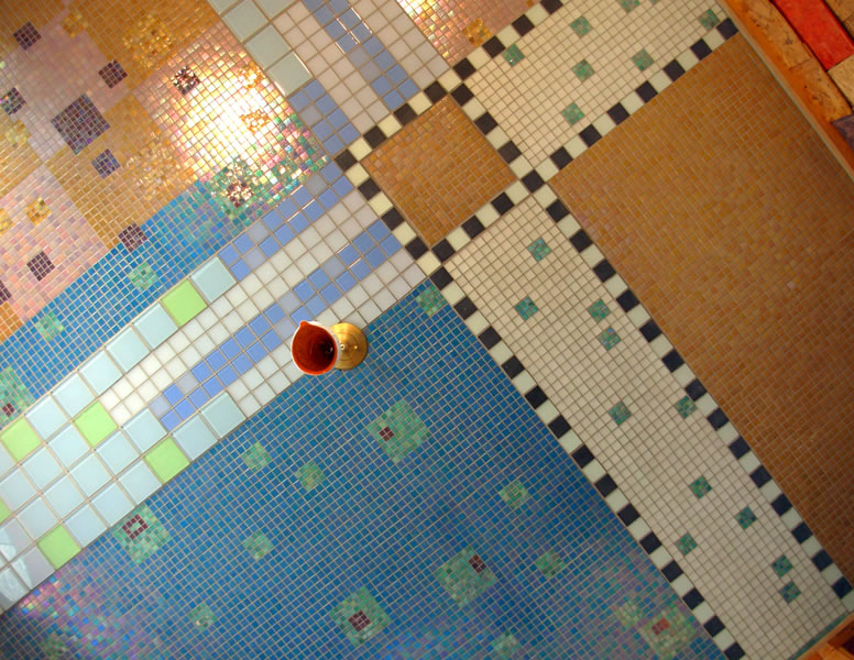 Patchwork mosaic ceiling panels in blue, orange, pink, and tan separated by black-and-white checkered borders