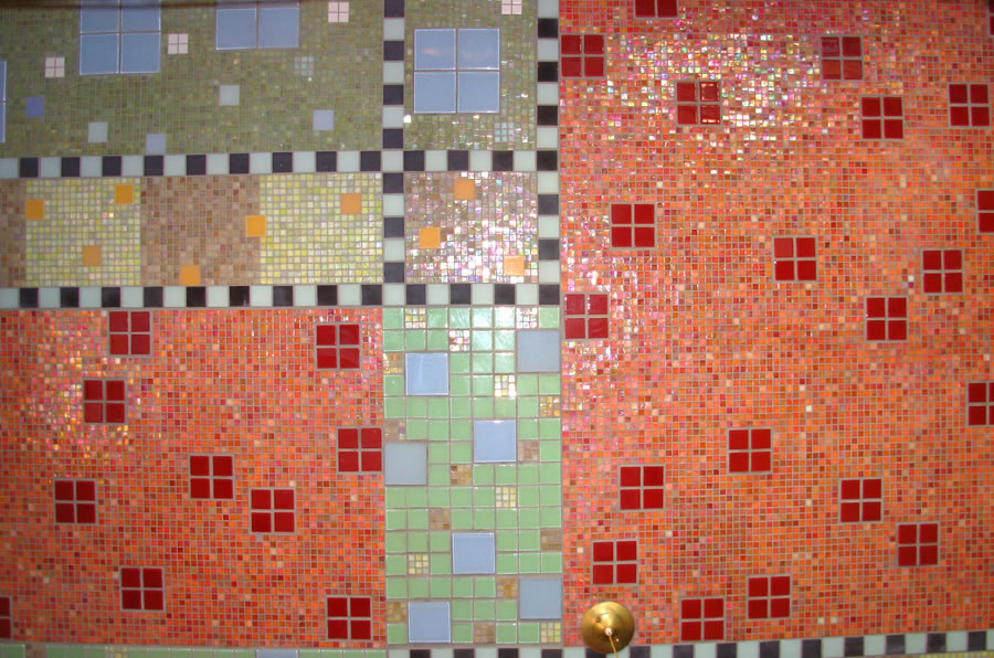 Mosaic wall section in olive green and salmon iridescent glass tile with red, blue, and yellow square accent tiles