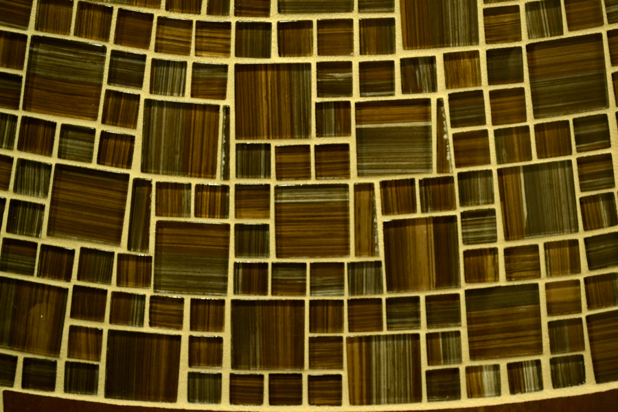 Close-up of the brown striped glass mosaic field — varied-size square tiles in deep brown, amber, and bronze with horizontal stripe pattern